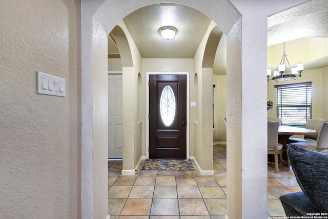 tiled foyer with an inviting chandelier and a textured ceiling