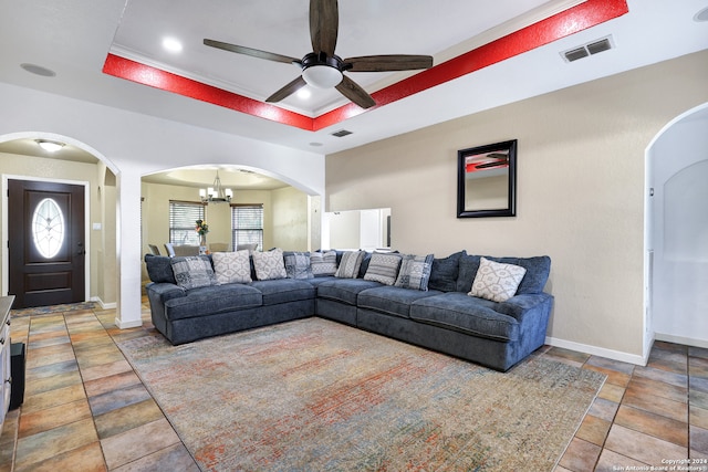 living room with ceiling fan with notable chandelier, a raised ceiling, and plenty of natural light