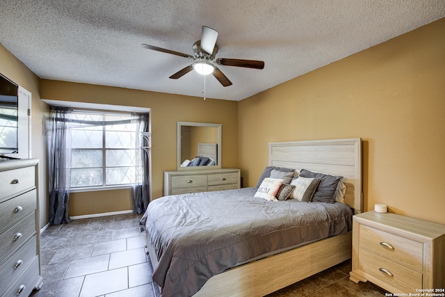 tiled bedroom with a textured ceiling and ceiling fan