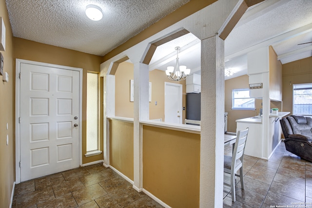 entryway featuring a textured ceiling, a chandelier, and vaulted ceiling