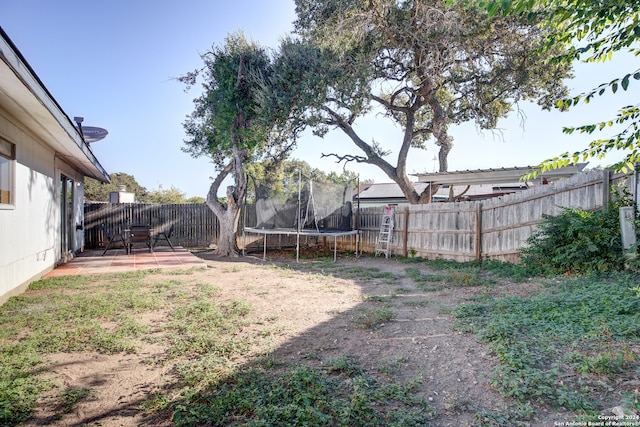 view of yard featuring a trampoline and a patio