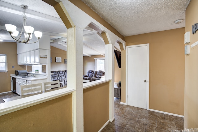 kitchen featuring lofted ceiling, sink, a textured ceiling, decorative light fixtures, and black dishwasher