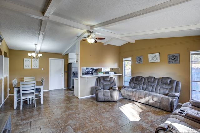 living room featuring ceiling fan with notable chandelier, a wealth of natural light, vaulted ceiling with beams, and a textured ceiling