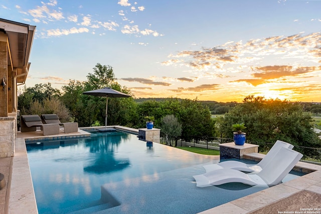 pool at dusk featuring a patio area