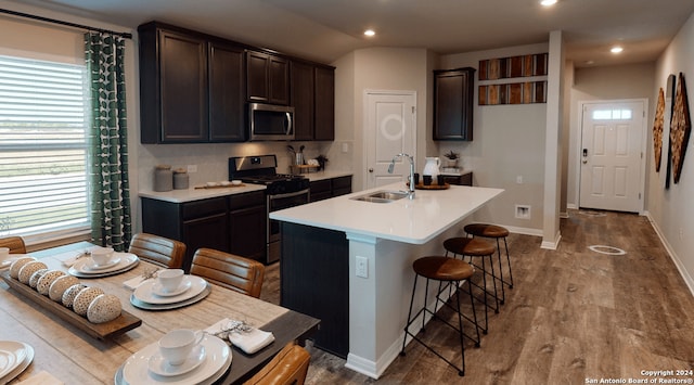 kitchen featuring sink, tasteful backsplash, a kitchen bar, a kitchen island with sink, and appliances with stainless steel finishes