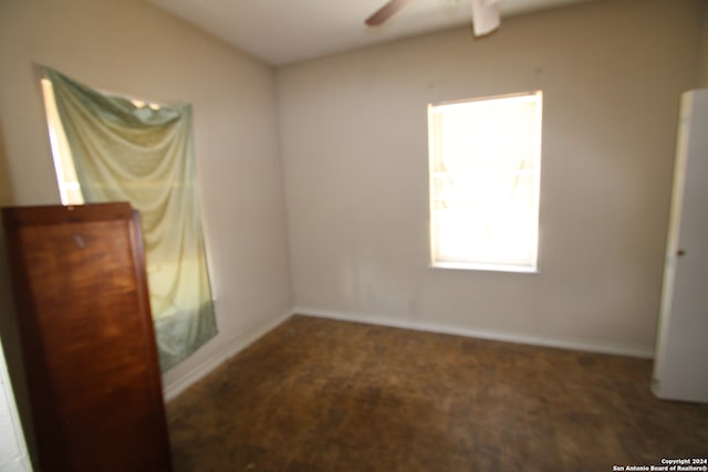 empty room featuring ceiling fan and dark colored carpet