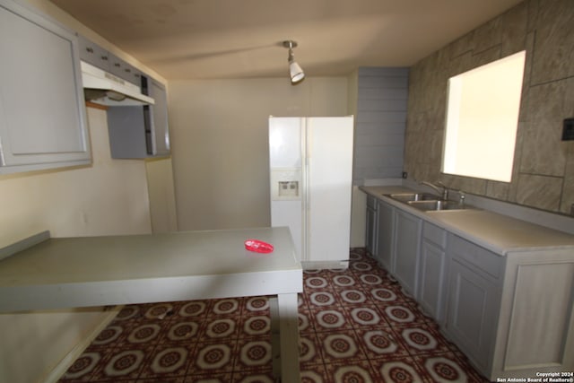 kitchen with gray cabinets, white refrigerator with ice dispenser, and sink