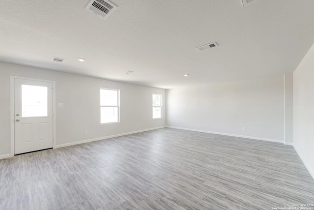 empty room featuring a textured ceiling and light wood-type flooring