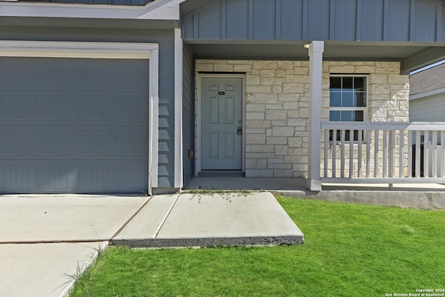 view of exterior entry featuring a lawn and a garage