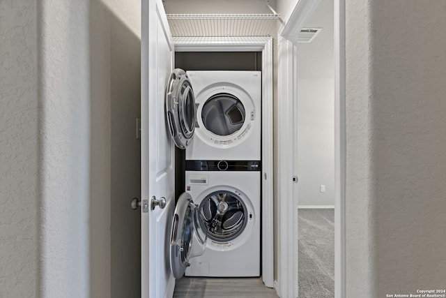 clothes washing area with light carpet and stacked washer / dryer