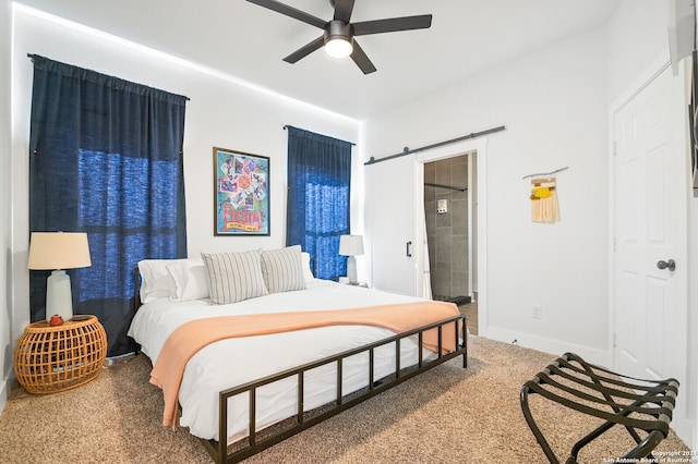 carpeted bedroom featuring ceiling fan, connected bathroom, and a barn door