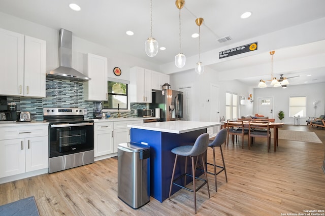 kitchen with white cabinets, stainless steel appliances, and wall chimney range hood