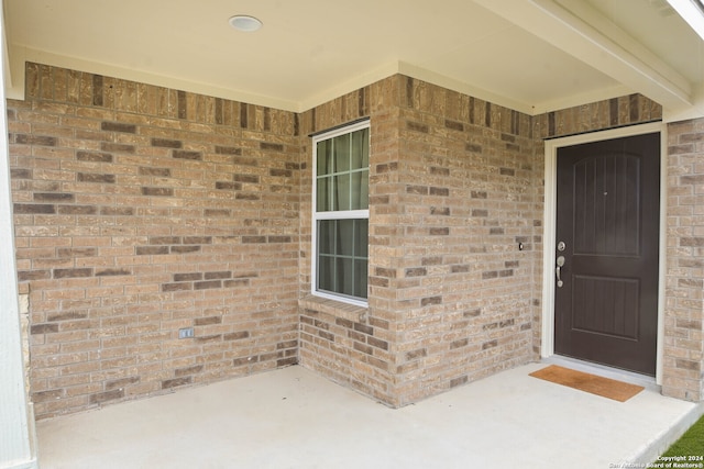 view of exterior entry with a patio area