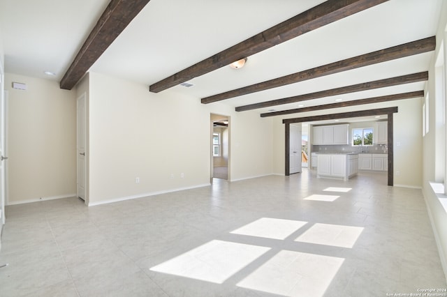 unfurnished room with beam ceiling