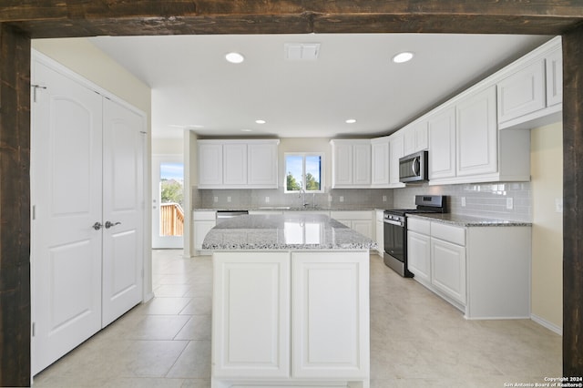 kitchen with light stone countertops, appliances with stainless steel finishes, white cabinets, and decorative backsplash