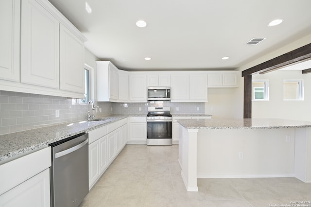 kitchen featuring light stone countertops, sink, stainless steel appliances, and white cabinets