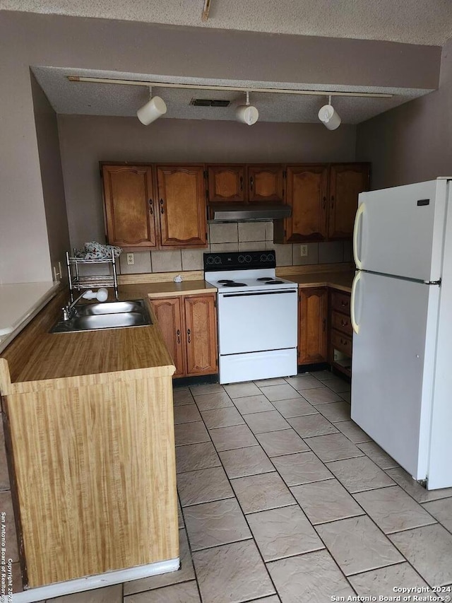 kitchen featuring a textured ceiling, tasteful backsplash, sink, and white appliances