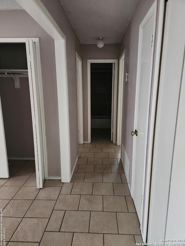 hall with light tile patterned floors and a textured ceiling