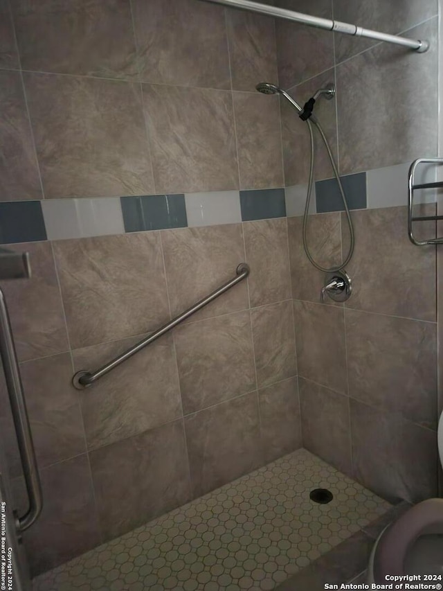 bathroom featuring tiled shower and toilet