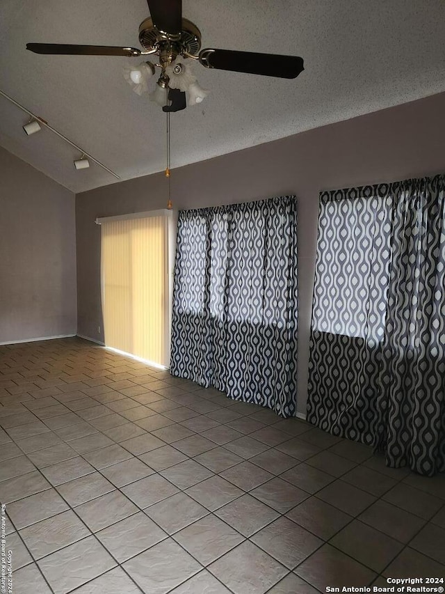 tiled spare room featuring ceiling fan, vaulted ceiling, and a textured ceiling