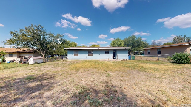 rear view of house with a shed and a yard