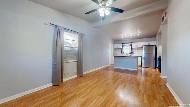 kitchen featuring ceiling fan, backsplash, white cabinetry, stainless steel refrigerator, and light wood-type flooring