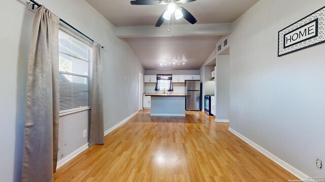 kitchen featuring decorative backsplash, light hardwood / wood-style floors, white cabinets, stainless steel appliances, and ceiling fan