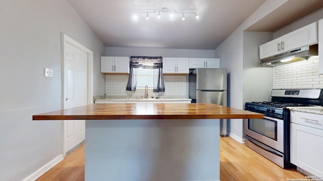 kitchen featuring decorative backsplash, appliances with stainless steel finishes, wooden counters, and white cabinetry