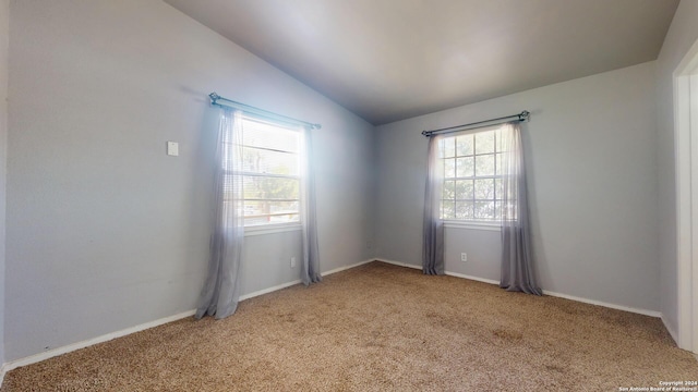 spare room featuring light carpet and lofted ceiling