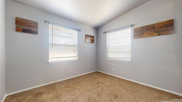 carpeted empty room with lofted ceiling