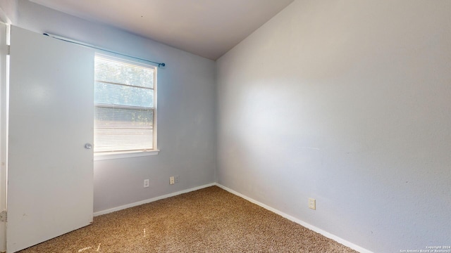 carpeted empty room featuring lofted ceiling