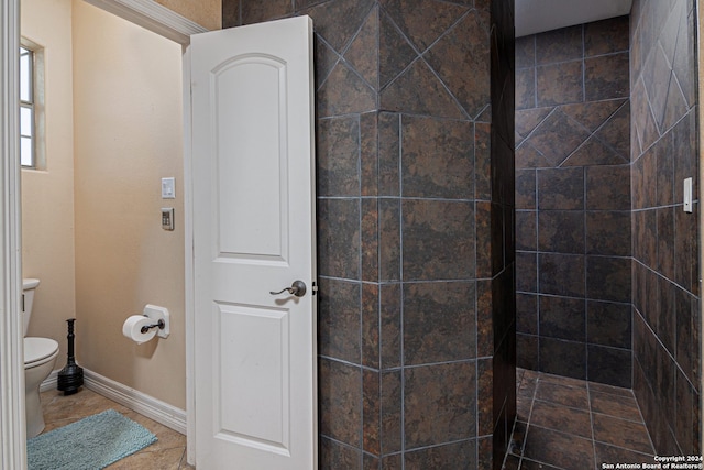 bathroom featuring tiled shower, toilet, and tile patterned flooring