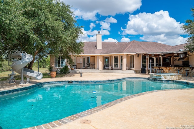 view of pool featuring an in ground hot tub, a water slide, and a patio area