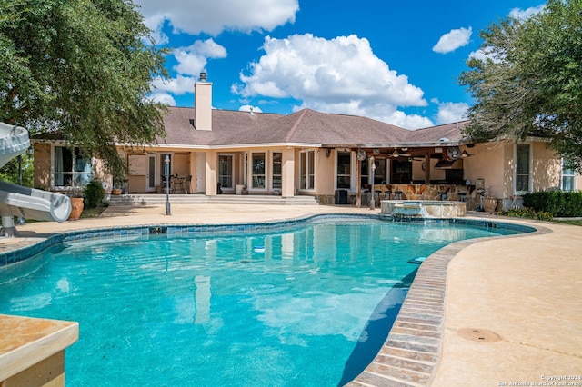 view of swimming pool with a patio, a water slide, and an in ground hot tub