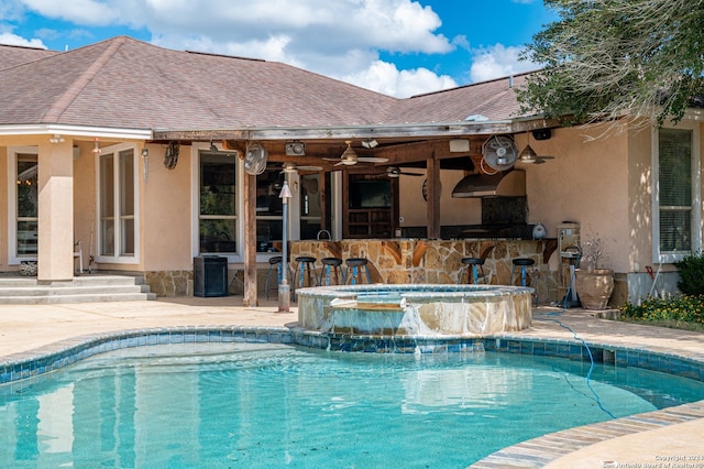 view of swimming pool with an outdoor bar, a patio, pool water feature, an in ground hot tub, and ceiling fan