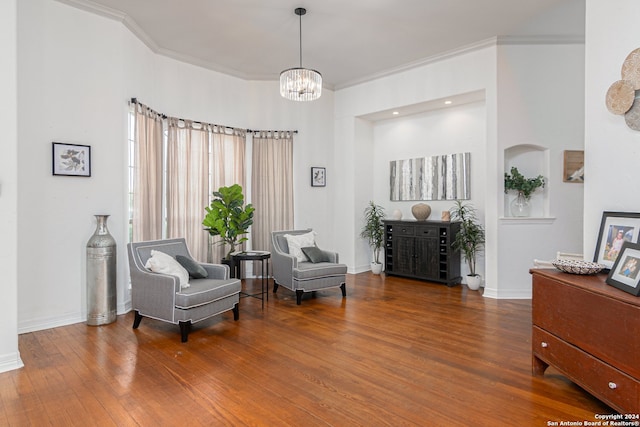 living area featuring wood-type flooring, crown molding, and a notable chandelier