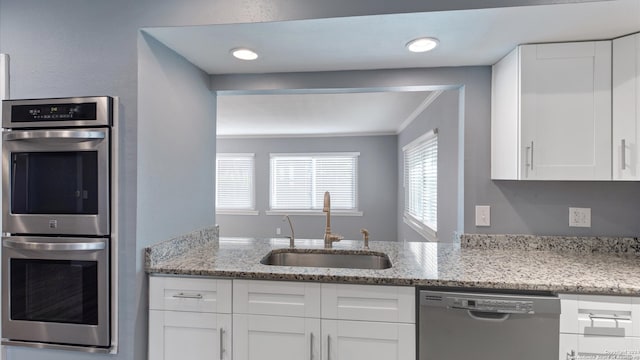 kitchen with appliances with stainless steel finishes, sink, and white cabinetry