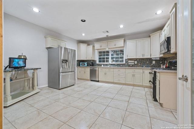 kitchen featuring appliances with stainless steel finishes, decorative backsplash, light tile patterned floors, and cream cabinetry