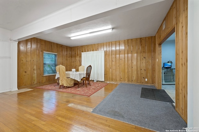 dining area featuring wood walls, decorative columns, and hardwood / wood-style flooring