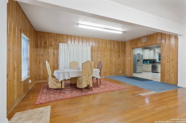 dining room with light wood-type flooring and wood walls