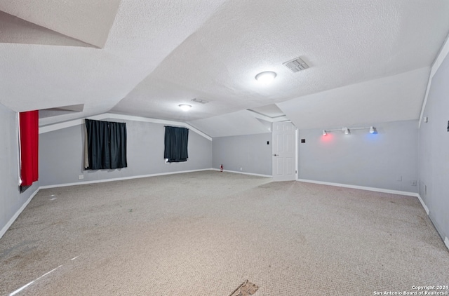 additional living space with carpet, a textured ceiling, and vaulted ceiling