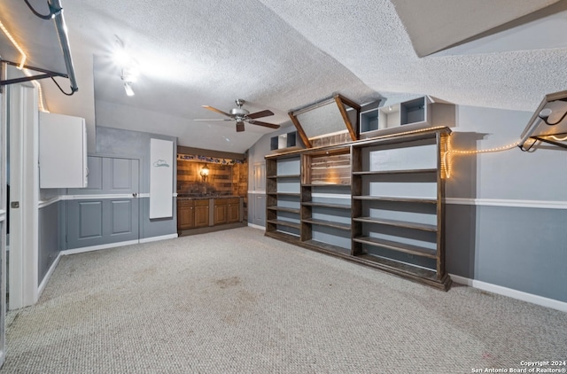 interior space with a textured ceiling, lofted ceiling, carpet flooring, and ceiling fan