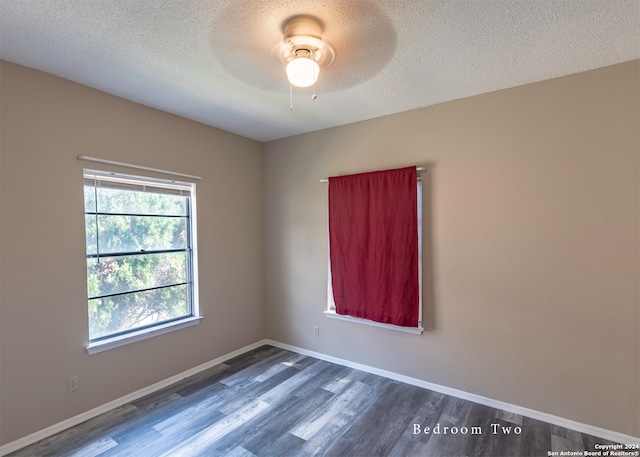 unfurnished room with a textured ceiling, ceiling fan, and dark hardwood / wood-style flooring