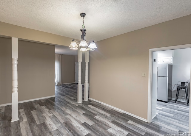 unfurnished dining area featuring a textured ceiling and dark hardwood / wood-style flooring