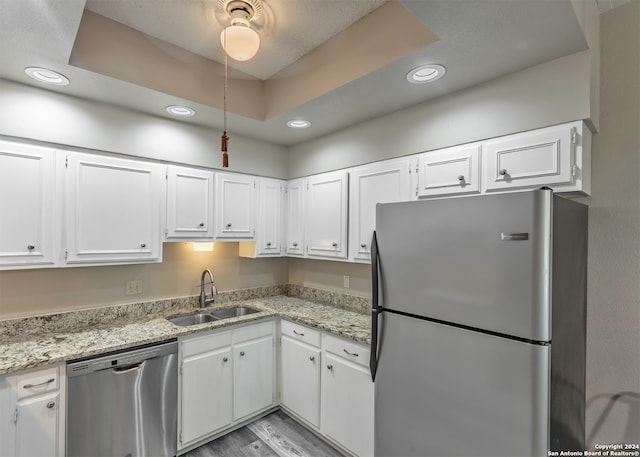 kitchen with light stone counters, white cabinets, stainless steel appliances, and sink