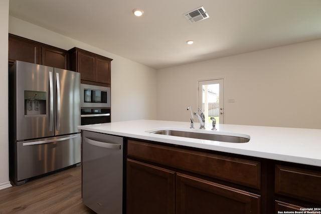 kitchen with dark brown cabinetry, dark hardwood / wood-style floors, sink, and stainless steel appliances