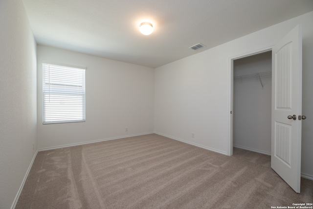 unfurnished bedroom featuring light colored carpet and a closet