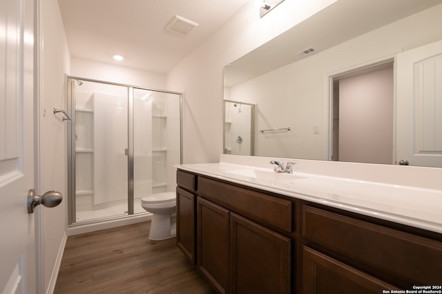 bathroom with vanity, toilet, a shower with shower door, and hardwood / wood-style floors