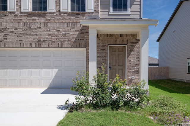 property entrance featuring a garage and a lawn