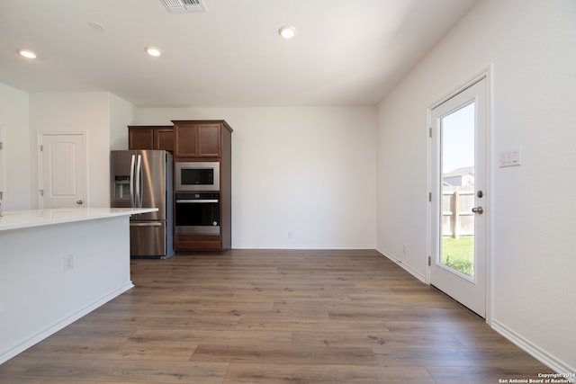 kitchen with dark brown cabinetry, stainless steel appliances, and dark hardwood / wood-style flooring